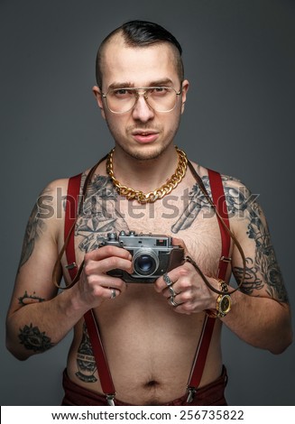 Man with tattoo holding photo camera. Isolated on grey.