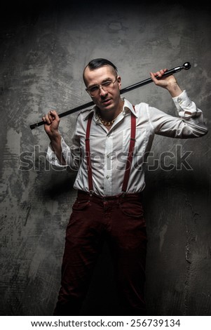 Male in red pants and white t shirt holding cane.