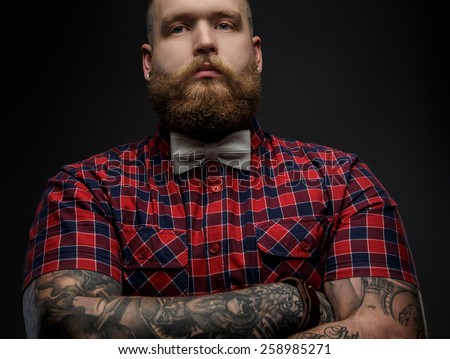 Portrait of male in red shirt and grey bow tie with tattoos on his hands. Isolated on black. - Stock Image - Everypixel