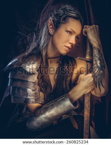 Portrai of mystic  elf woman with sword, armor and tattoo on her hand.