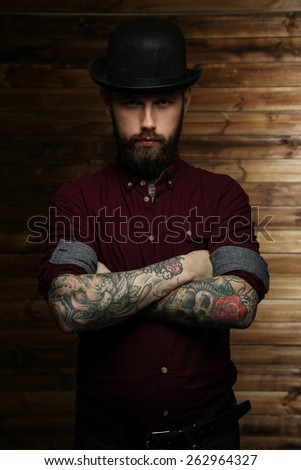 Tattoed male posing over wood wall