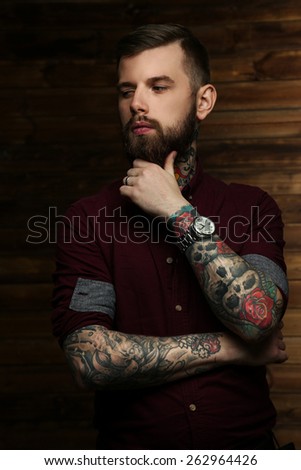 Tattoed male posing over wood wall