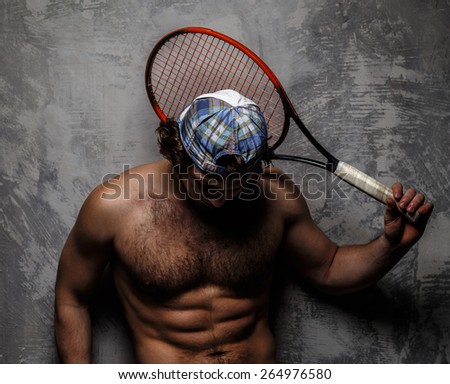 Male in white shorts with tennis racket over grey wall.
