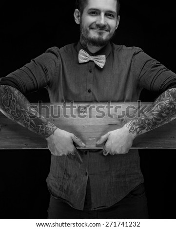 Smiling guy in shirt and bow tie holding wood board. Isolated on black