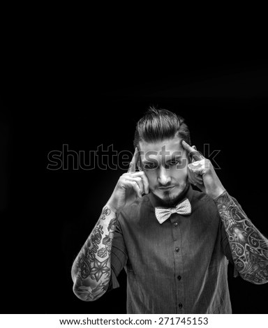 Portrait of a man in shirt with  bow tie and tattooes on his hands. Isolated on black.