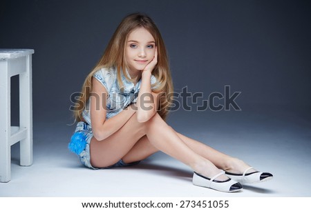Young long haired girl in short and shirt sitting on a floor.