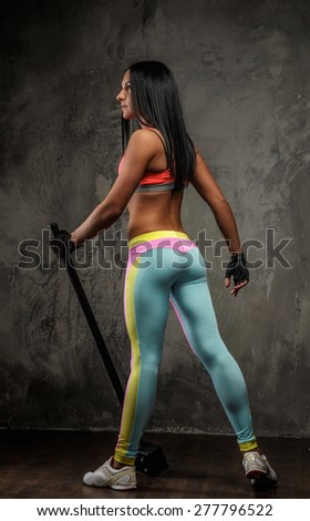 Fitness woman in colorful sportswear. Photo from her back on grey background