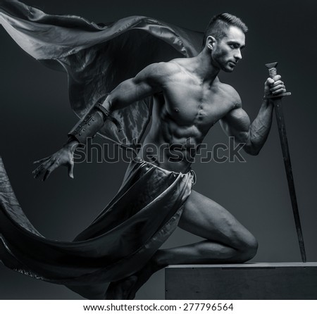 Black and white photo of muscular guy with sword on grey background