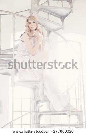 Blond female in white dress posing on stairs in soft light