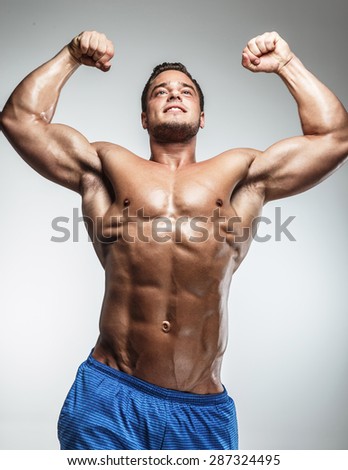 Awesome muscular guy in blue shirts showing his muscles. Isolated on grey background