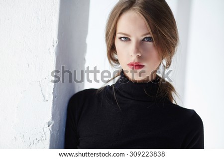 Classic portrait of woman in black clothing over light background.
