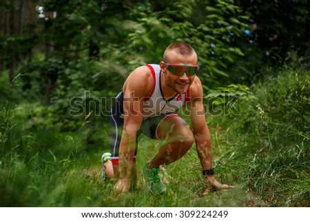 Running man in sportswear in green summer forest.