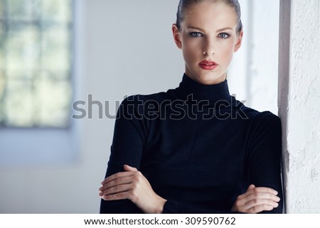 Brunette woman in black clothing with arms crossed.