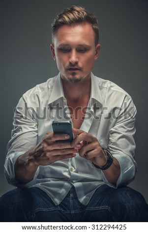 Attractive guy in white shirt with mobile phone. Isolated on grey