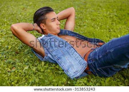Casual man in jeans jacket lying on the grass.