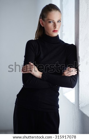 Portrait of brunette woman with crossed arms in black costume.