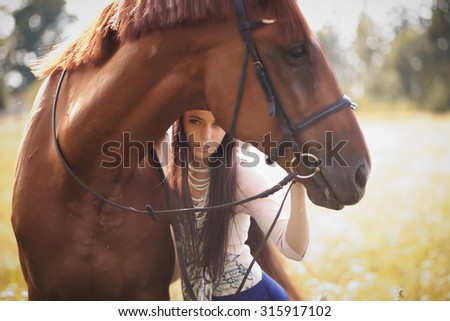 Fashion woman with long brown hair posing with brown horse.