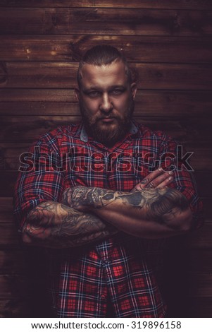 Portrait of serious brutal man with beard and tattooes. Crossed arms.