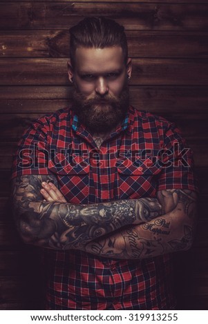 Portrait of serious brutal man with beard and tattooes. Crossed arms.