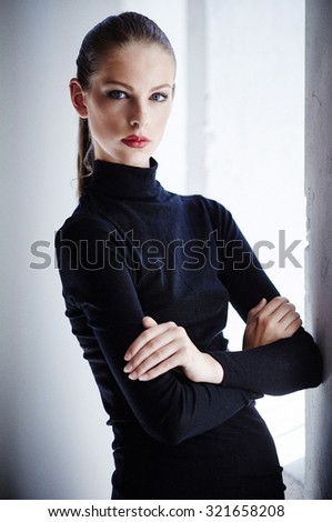 Slim brunette woman in black sweater. Crossed arms.