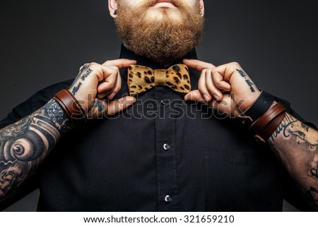 Part of man\'s face with beard and tattooed arms.