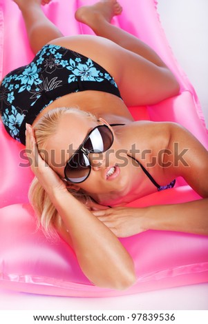 Image of woman in sunglasses on pink mattress