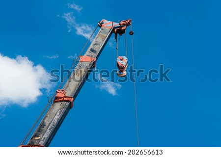 truck crane boom with hooks and scale weight above blue sky