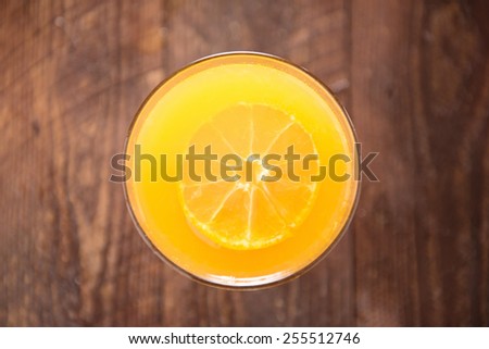 Top orange juice in glass, fresh fruits on wooden background.