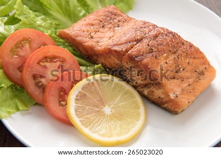 Grilled salmon fillet cooked BBQ and served with fresh herbs and lemon