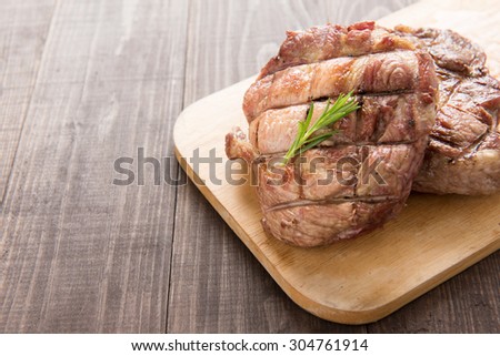 Grilled pork steak on a wooden background.