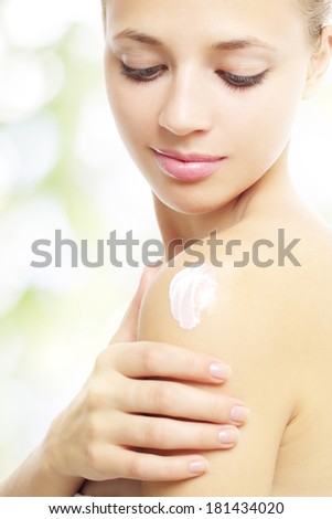 girl applying cream on shoulder on a light background