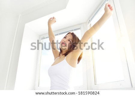 Girl stretching in the morning against the window