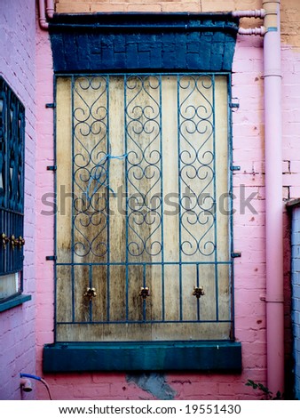 Boarded Up Window with Pink Wall and Security Iron bars Over Wood