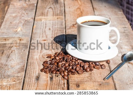 white coffee cup on wooden table background with strong dark shadow from the sunlight