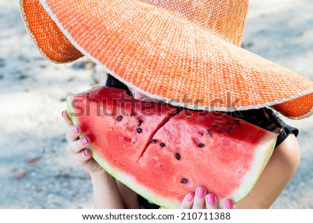 Beautiful girl eating fresh watermelon in big hat