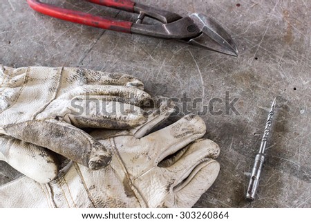 Protection gloves with a drill and a pair of claws on wooden desk. Construction office.