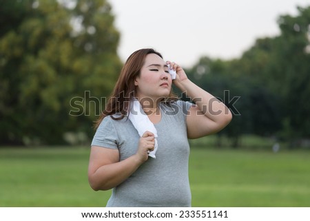 Obese woman wiping sweat while exercising.