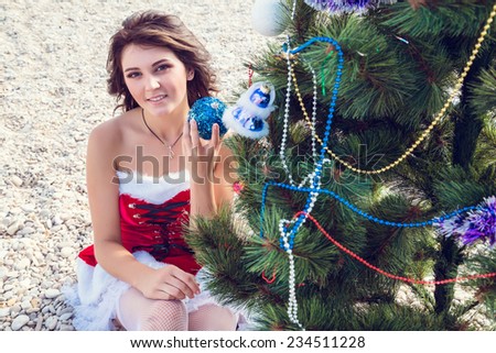 Resting woman on winter vacation in warm places. Happy Santa Girl with sunglasses on tropical beach. Beautiful brunette young woman smiling portrait in red Christmas hat celebrating New Year.
