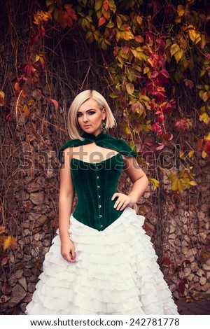 A woman like a princess in an vintage dress in fairy park. Mysterious woman dressed in scenic fashion clothes. Green labyrinth. Model plus