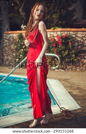 Young sexy woman floating on swimming pool in red dress. Beautiful rich lady who was strangled and thrown off into the water, but she is alive