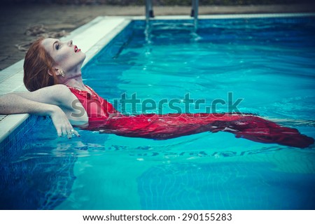 Young sexy woman floating on swimming pool in red dress. Beautiful rich lady who was strangled and thrown off into the water