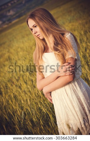 Healthy beautiful woman walking outdoors. Alluring young woman in wheat field, delicate sensual woman on nature. perfect skin, curly hair.