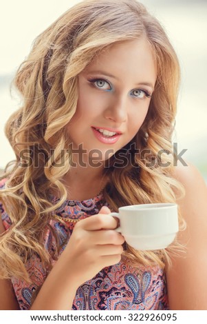 A lovely young girl with blond hair eating dessert and drinking tea in a cafe
