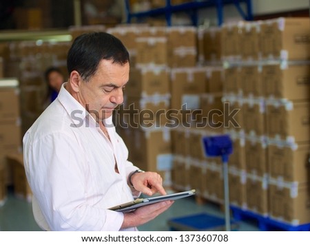 Manager checks the number of the boxes with goods in stock in Chinese factory