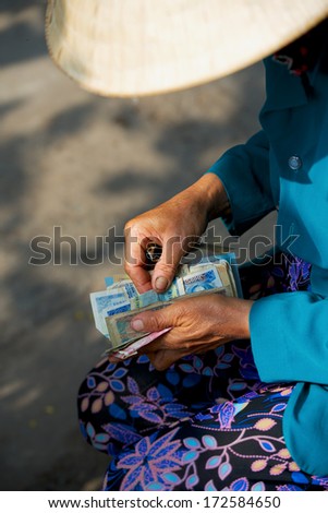 Vietnamese woman counts money in hands