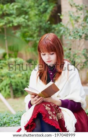 girl reading a book in the autumn garden