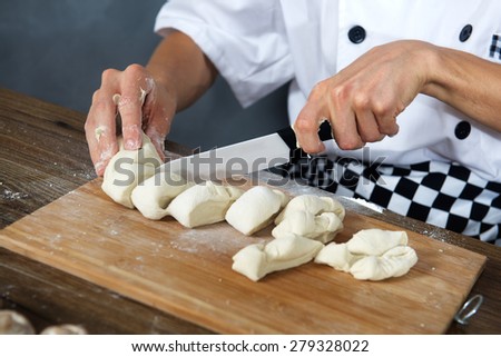 Chef cuts the dough for home made pizza