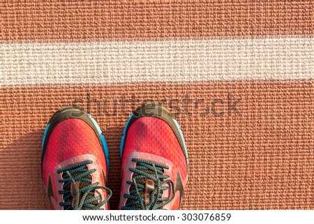 Red run shoes on a stadium surface.