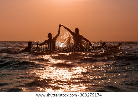 Group of young men shapes in the sea while sunset,