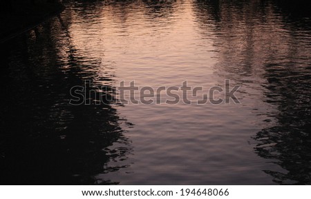 Dark Water Reflection on The Surface of A Pond with Pink Sky at Sunset